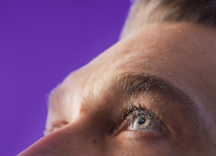 Extremely close up of blue eye with water droplets being discharged representing tear evaporation